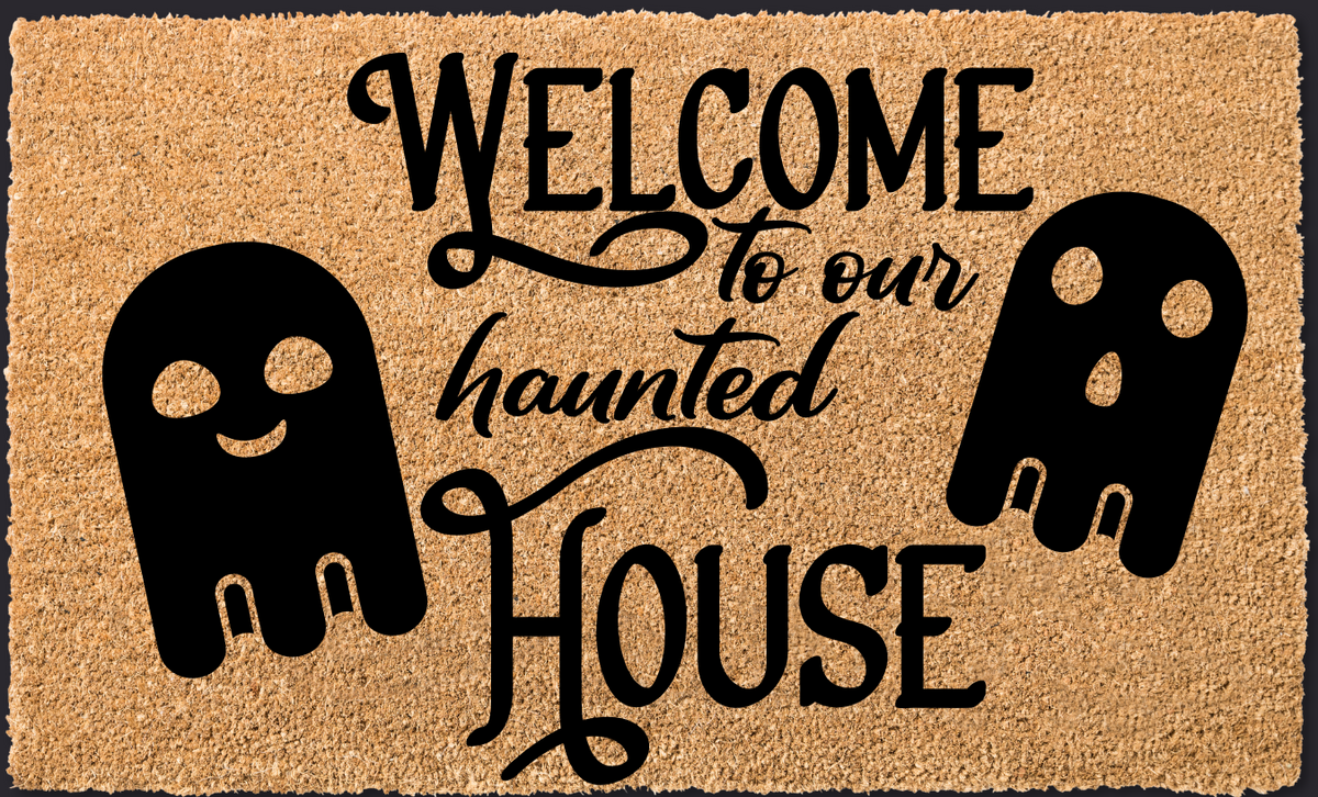 Doormat with 'Welcome to our haunted house' text and skull designs on a black background